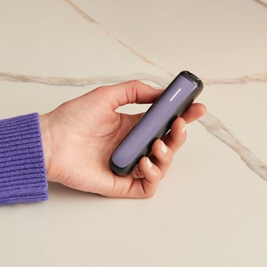 Ruka drži Ploom AURA uređaj sa Lavender prednjom maskom
