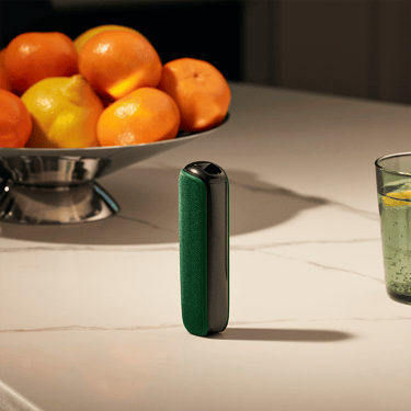 Ploom AURA Amazon Green zadnja maska na stolu pored činijesam sa voćem
