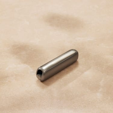 Prikaz izbliza prednje maske Ploom AURA dodatka u nijansi Lunar Silver na ravnoj površini.
