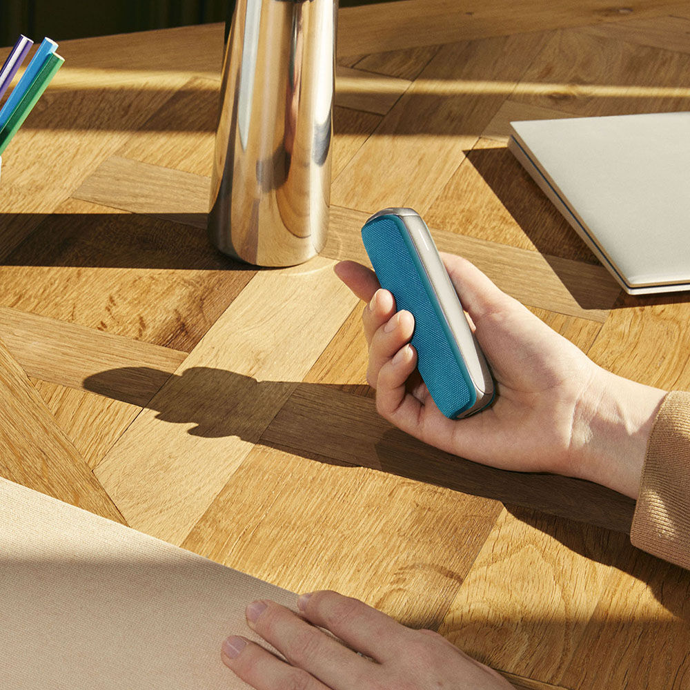 Ruka drži Ploom AURA uređaj sa aksesoarom Ocean Blue zadnjom maskom 
