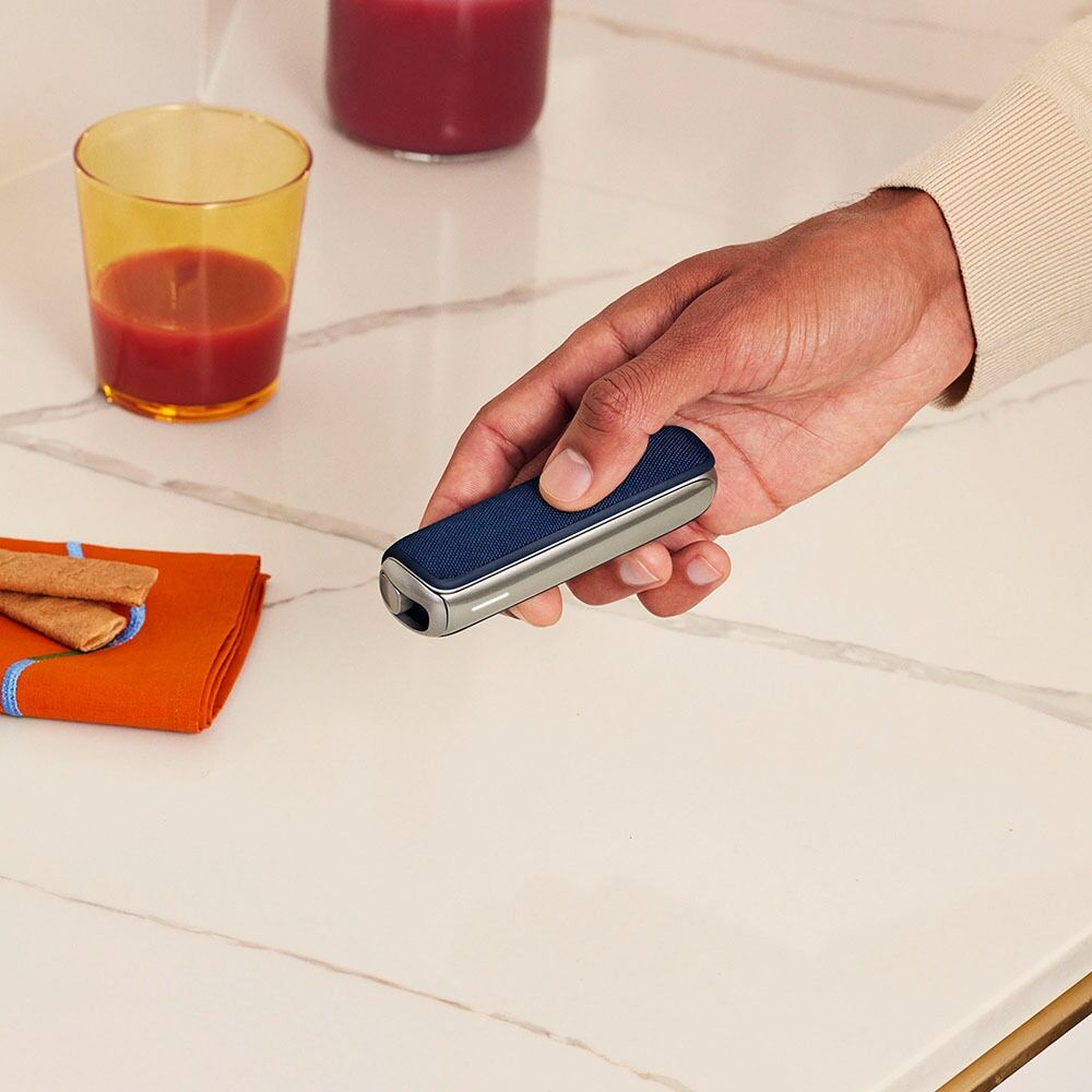 Ruka drži Ploom AURA uređaj sa Navy Blue zadnjom maskom
